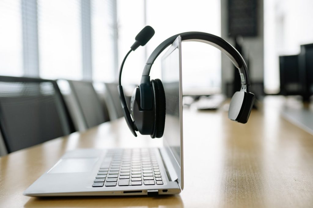 Sleek laptop with a wireless headset in a bright, modern office setting.